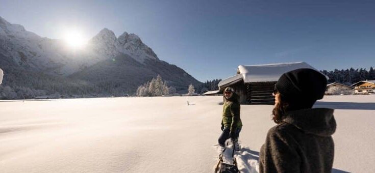 paar-auf-dem-weg-zum-schlittenfahren durch verschneites Schneefeld