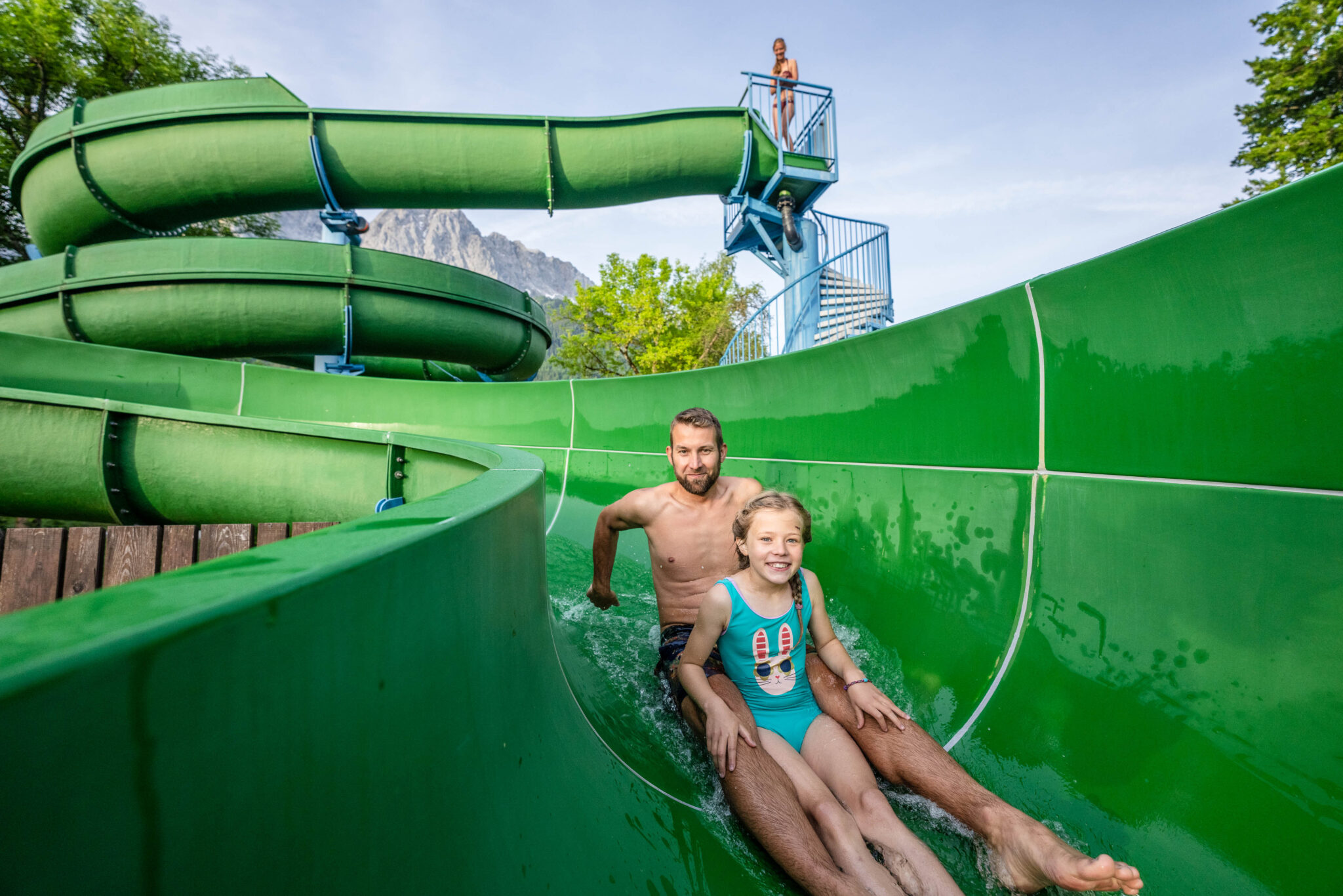 Mann mit Mädchen rutschenin Wasserrutsche des Freibades des Zugspitzbads Grainaus