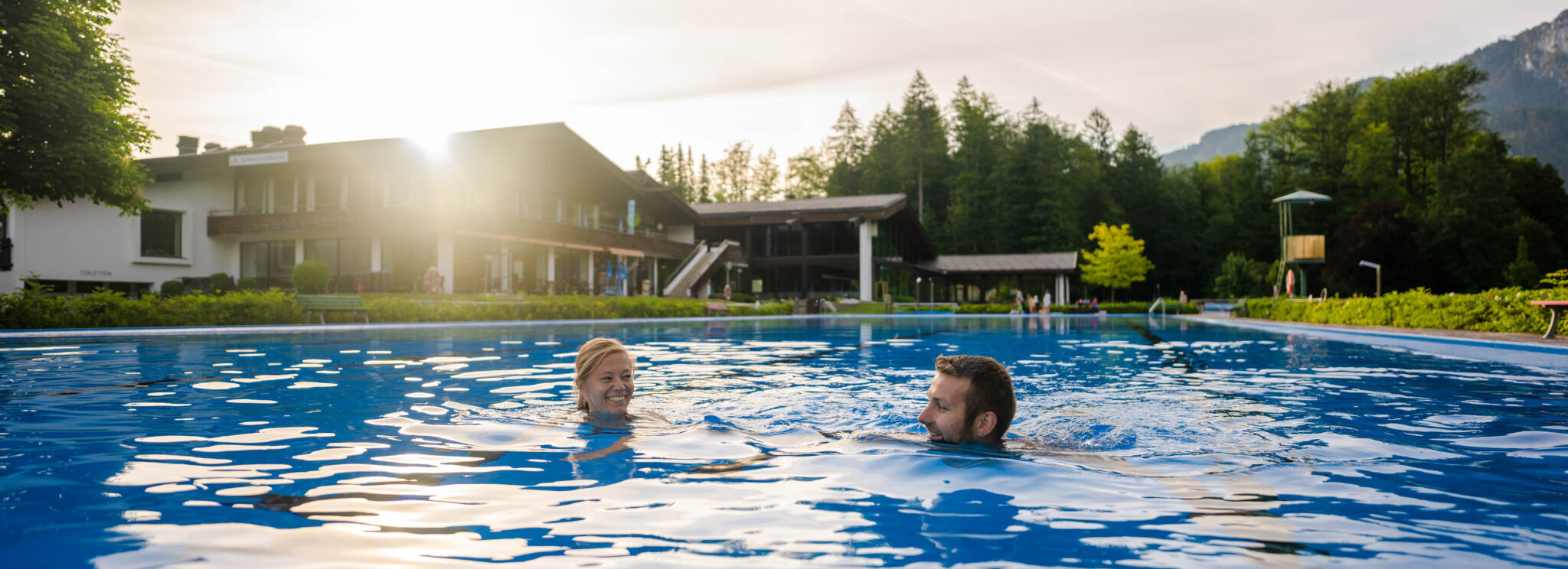 Schwimmendes Paar im Schwimmerbacken des Freibades in Grainau