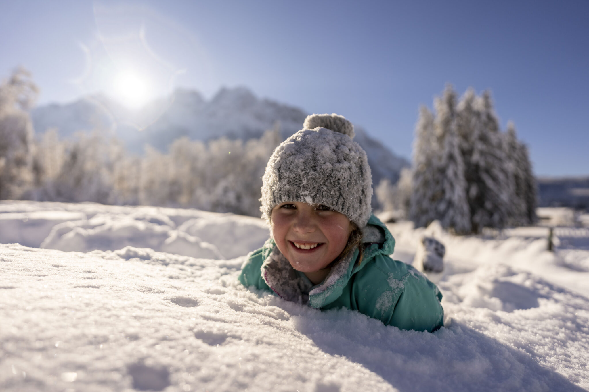 Mädchen im Schnee versinkend im Hintergrund unscharfe die Grainauer Berglandschaft