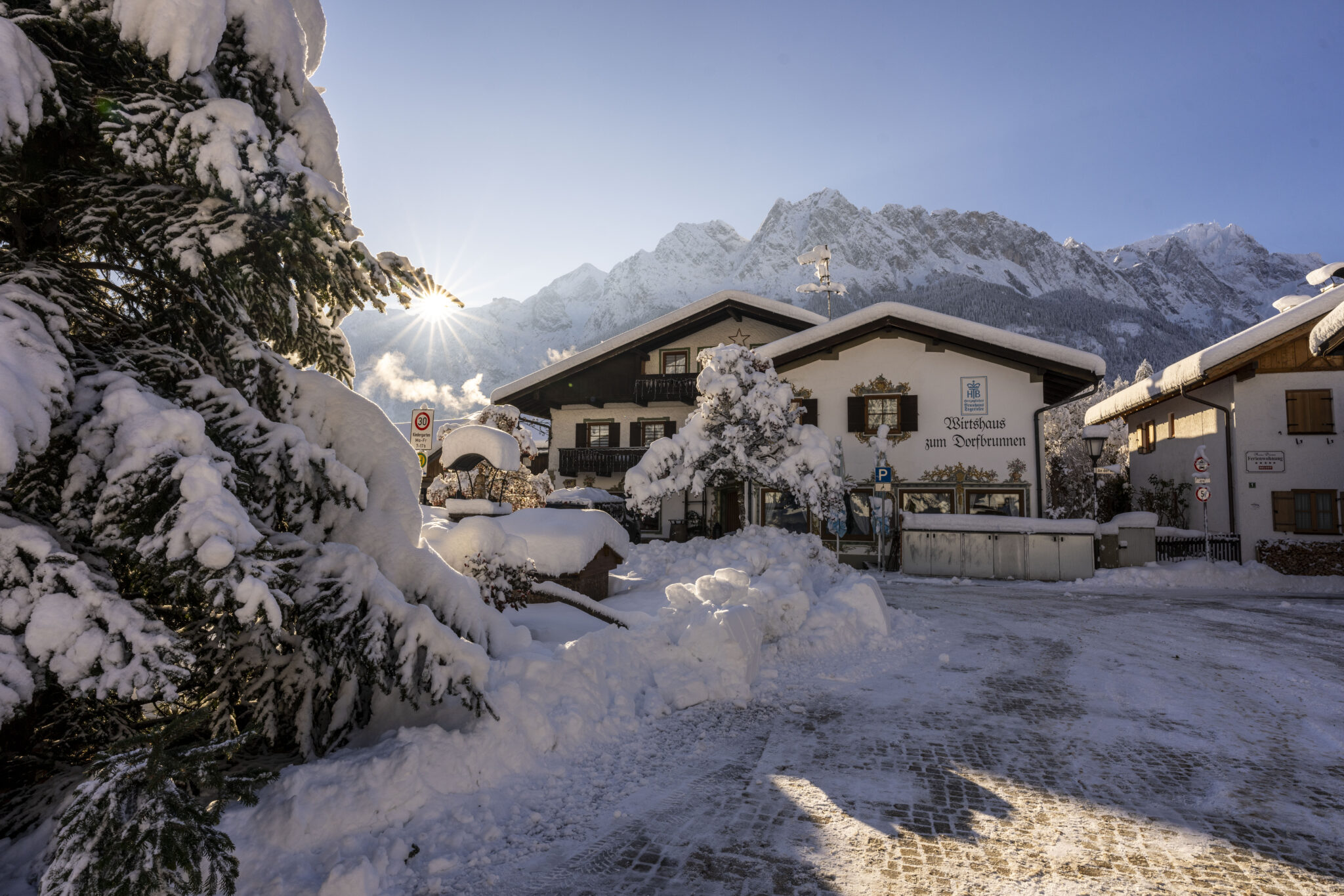 Untergrainauer Dorfplatz im winter mit viel Schnee im Hintergrund Berge