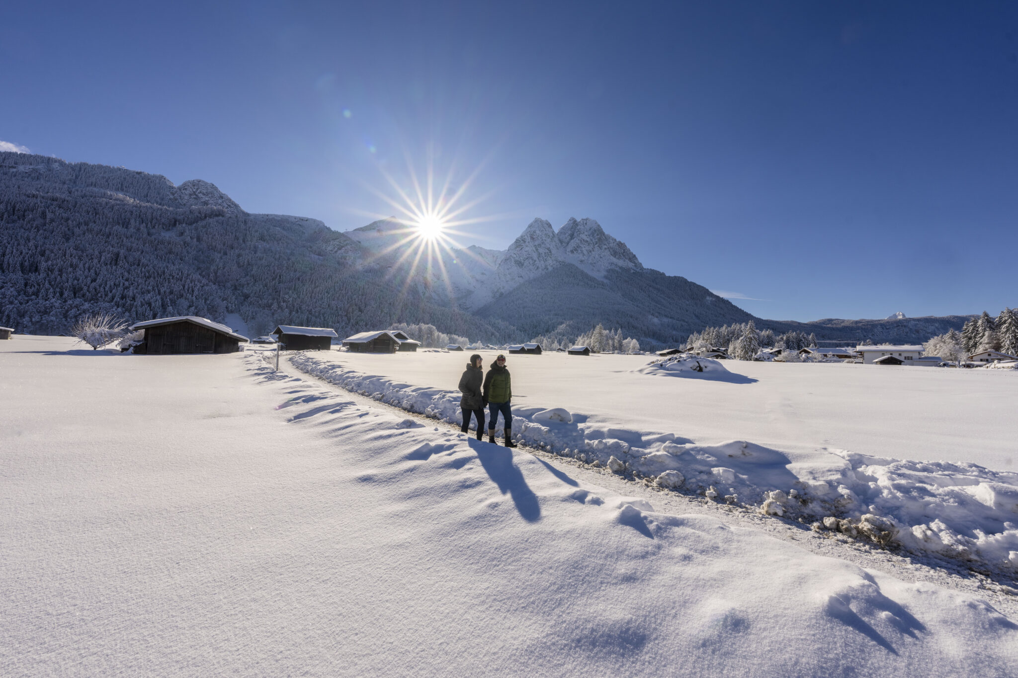 Paar spaziert im dick verschneiten Feld Hintergrund Berge mit Sonne