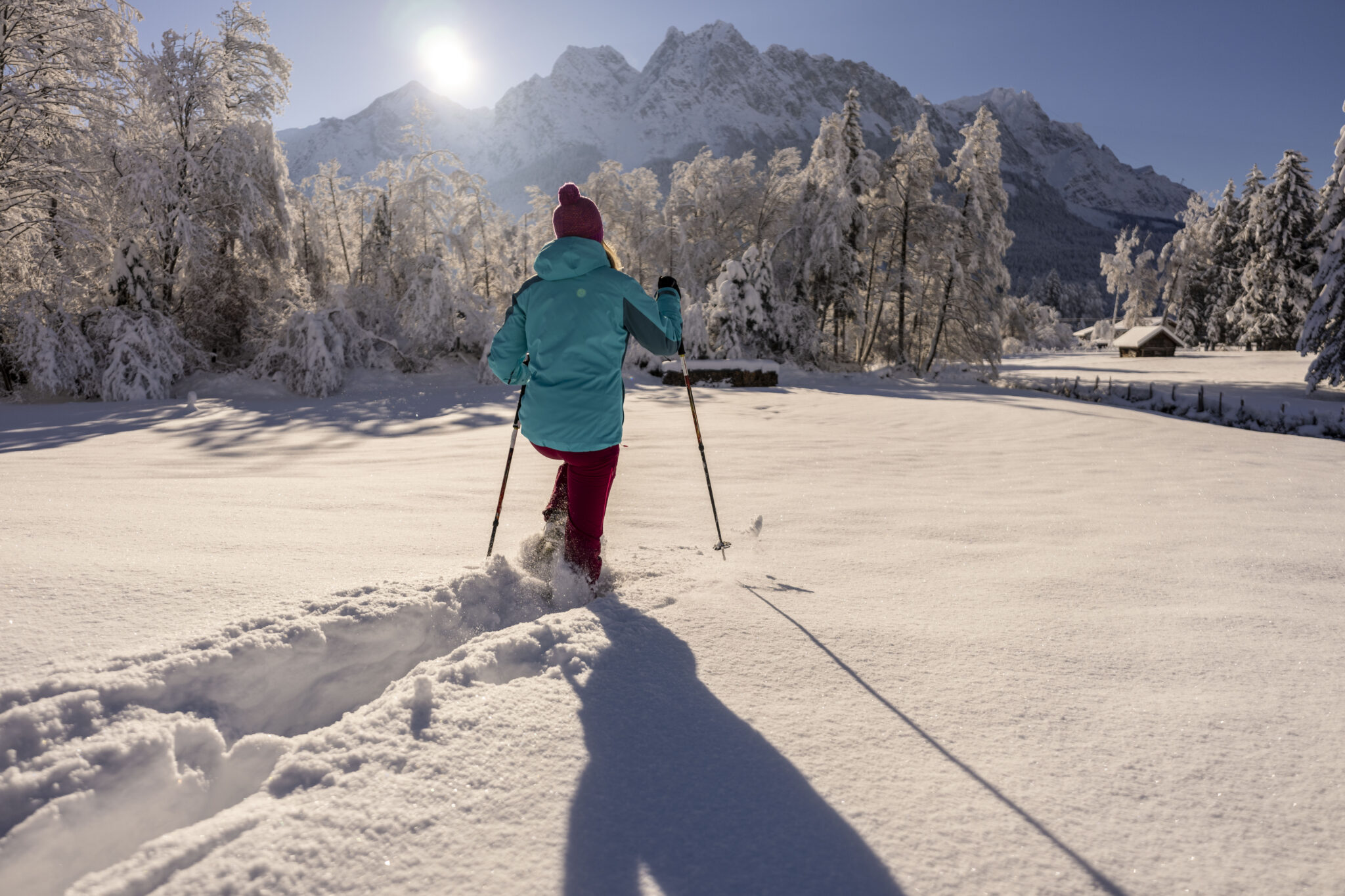 Dame mit Schneeschuhen im tiefen Schnee, Hintergrund sonne mit Wettersteingebirge