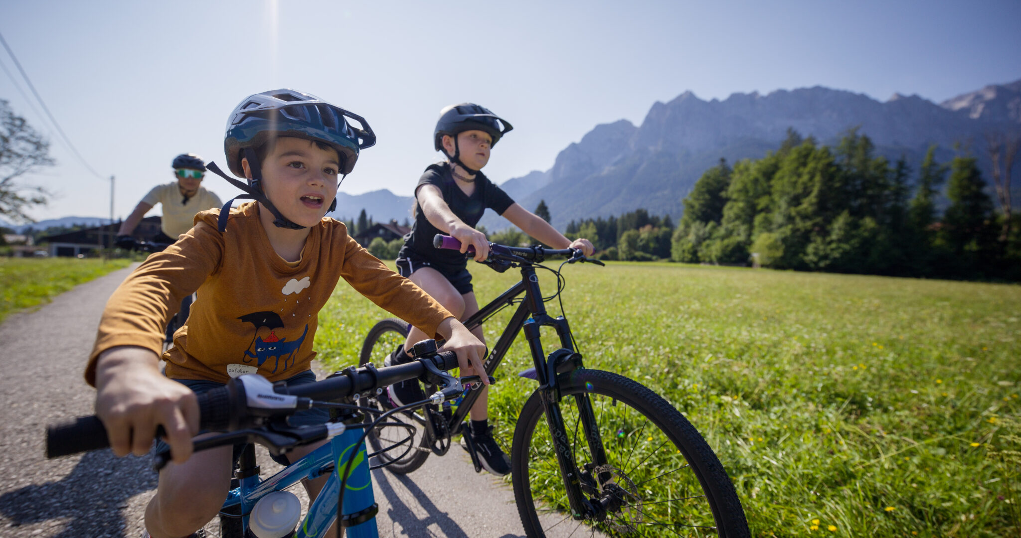 zwei Jinder auf Fahrrädern im Sommer im Hintergrund Wiese und Berge
